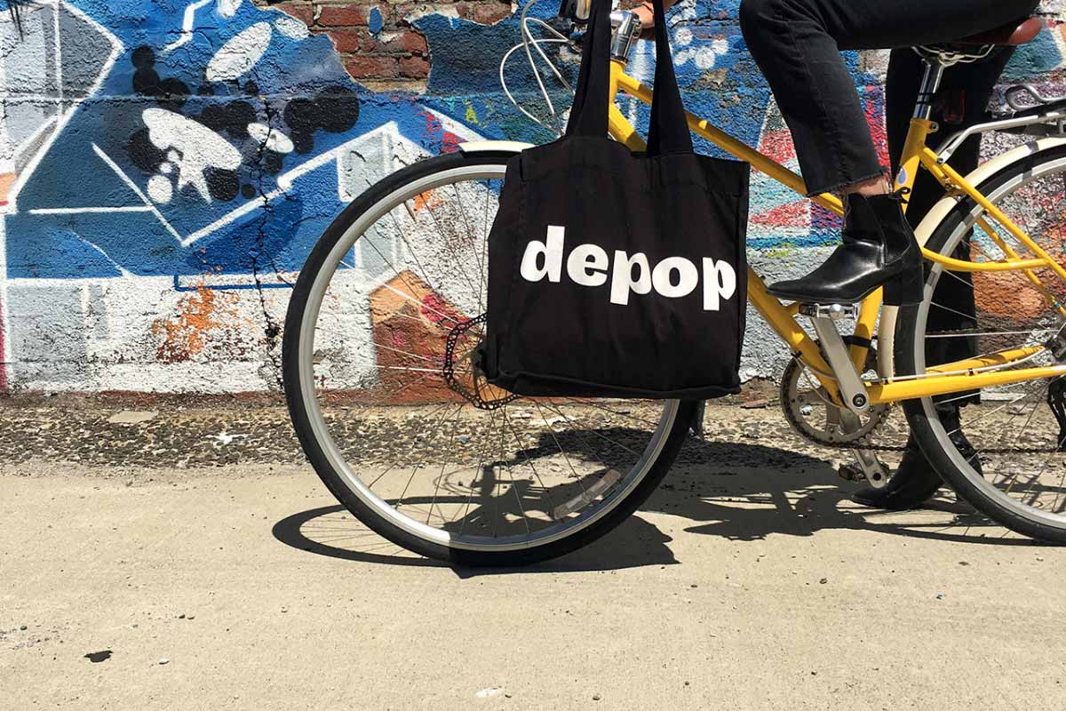 ragazza in bici con shopper nera Depop