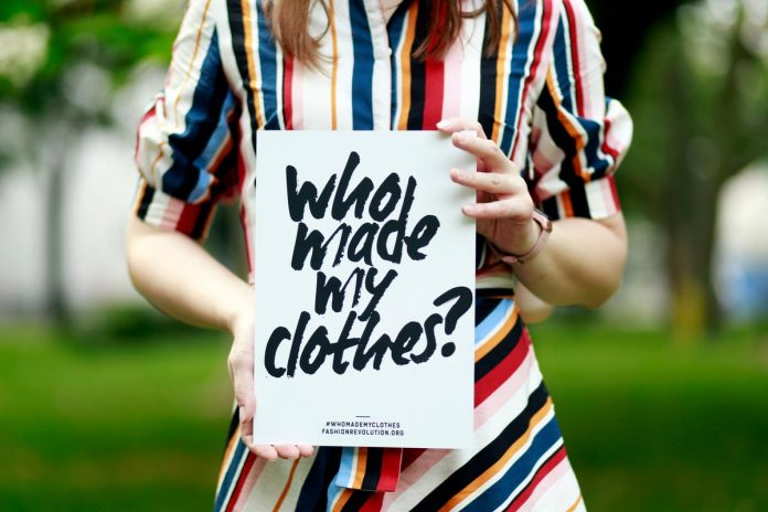 Donna che regge cartello con scritta Who made my clothes? Donna che regge cartello con scritta Who made my clothes?