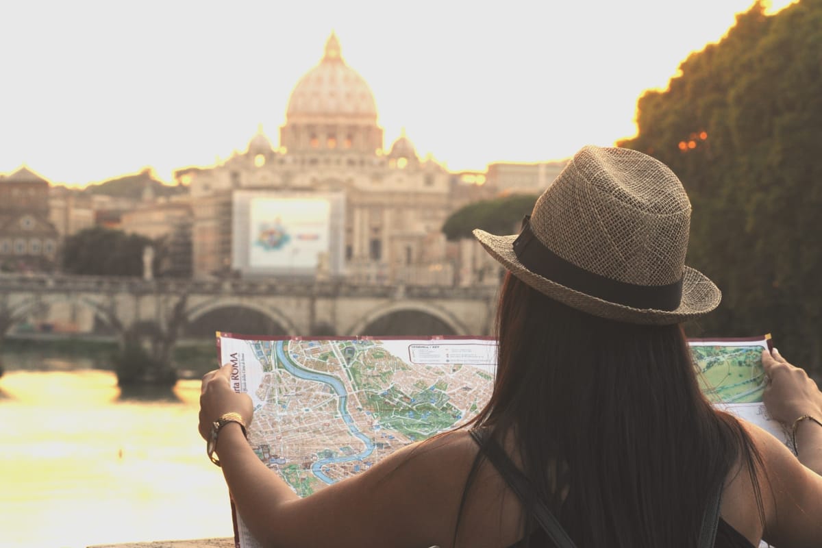 Ragazza guarda mappa di Roma con la cupola di San Pietro sullo sfondo