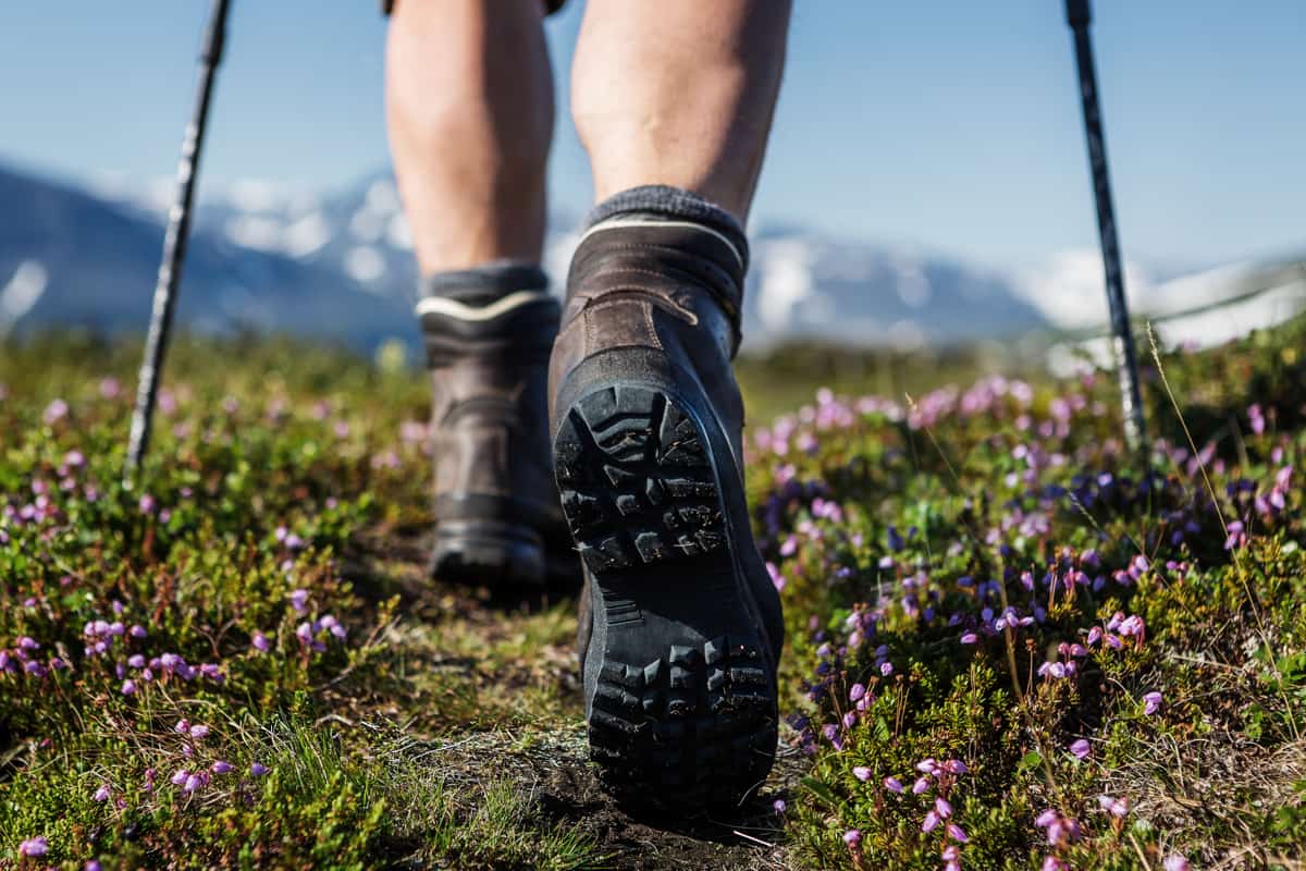 ragazza che cammina con scarponi da hiking su prato fiorito