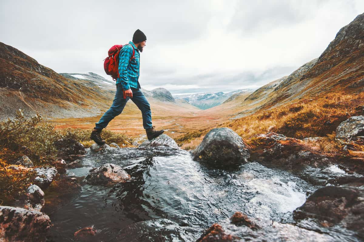 ragazzo fa hiking attraversando un ruscello