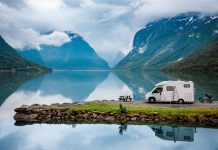 camper parcheggiato sulla riva di un lago tra le montagne