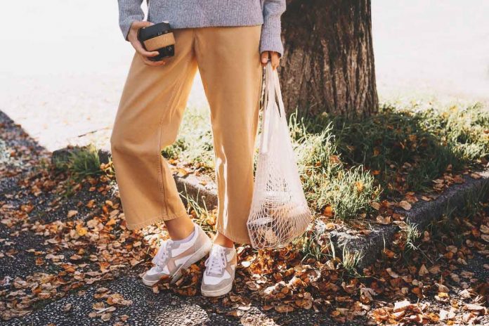 Capi ecosostenibili autunno-inverno Donna che indossa pantaloni beige in un bosco autunnale