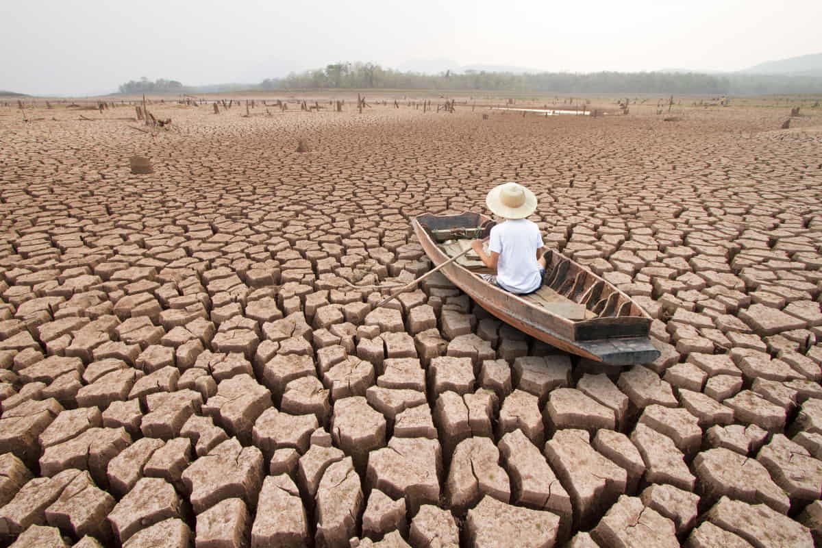 uomo in una barca su terreno desertificato