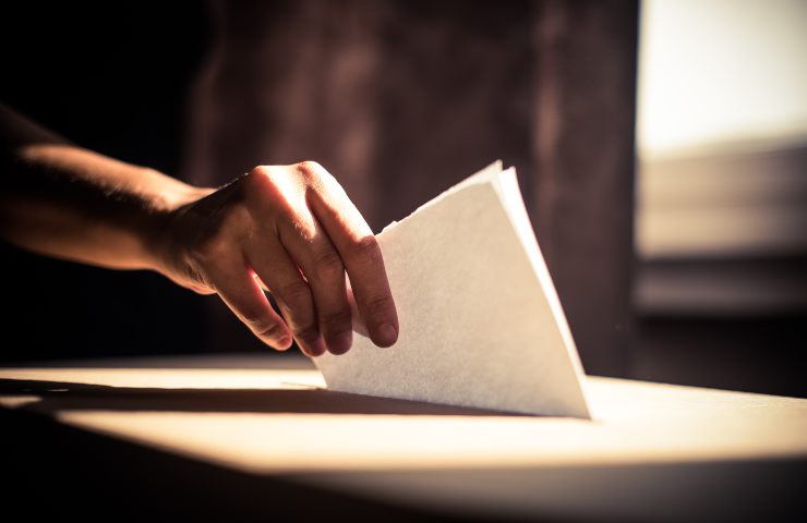 Un inserimento di una scheda in una urna elettorale