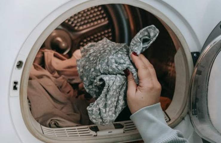 Una persona mette dei panni in lavatrice