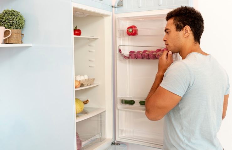 Un uomo davanti al frigorifero aperto