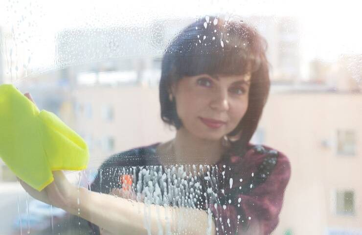 Una donna intenta a lavare un vetro