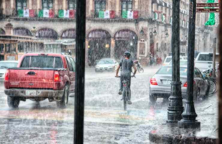 Una persona in bicicletta sotto alla pioggia