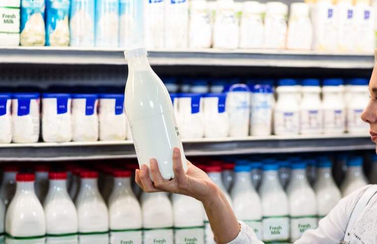 Una persona regge una bottiglia di latte al supermercato