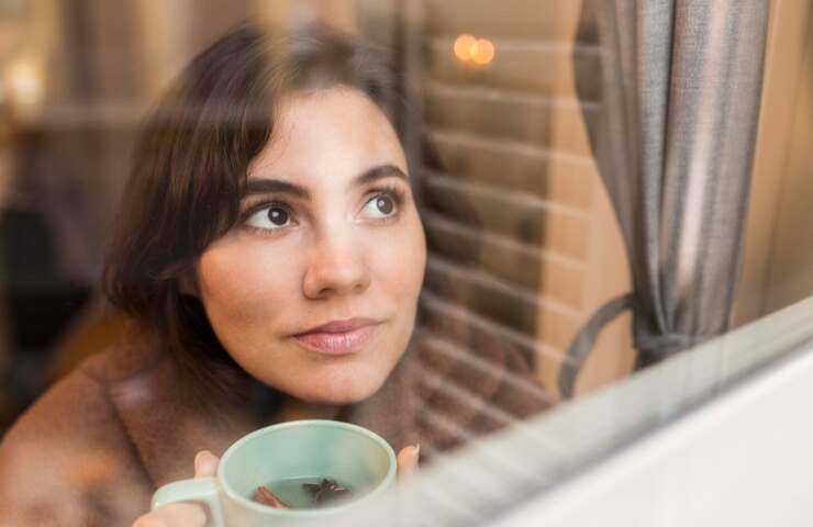 Una donna beve qualcosa di caldo in casa