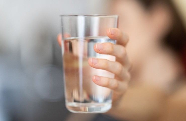 Una persona regge un bicchiere di acqua in mano