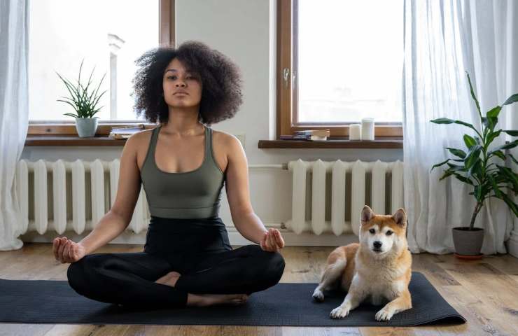 Una ragazza fa yoga assieme al suo cane