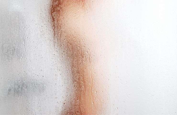 Una donna dietro al pannello di una doccia