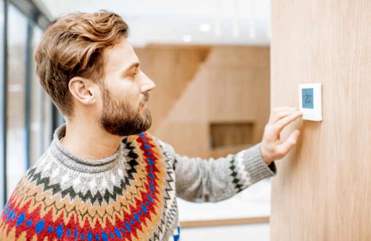 uomo che sistema il termostato